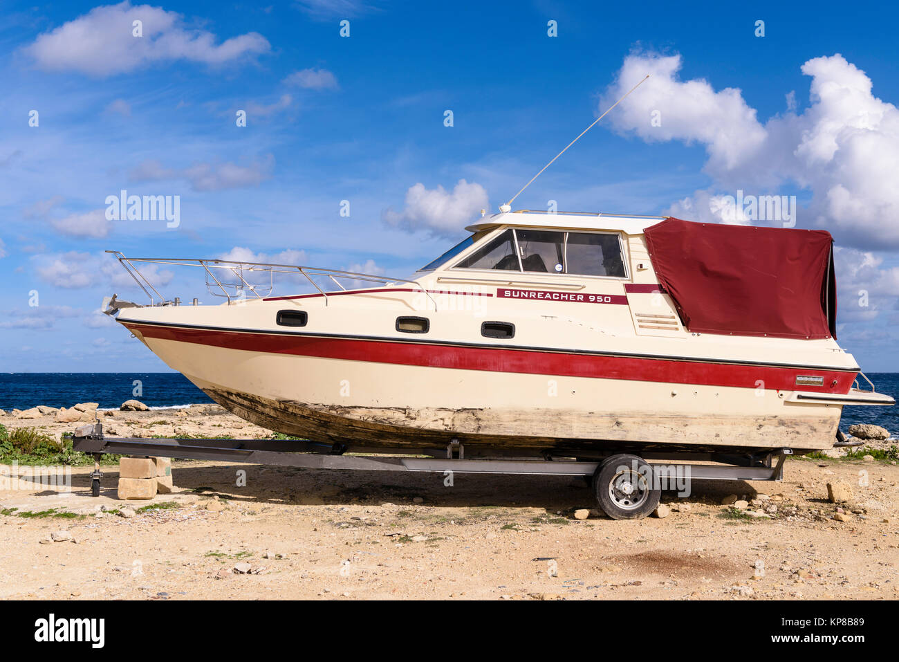 Ancienne Sunreacher 950 cabin cruiser sur une remorque stationnée à une côte rocheuse. Banque D'Images