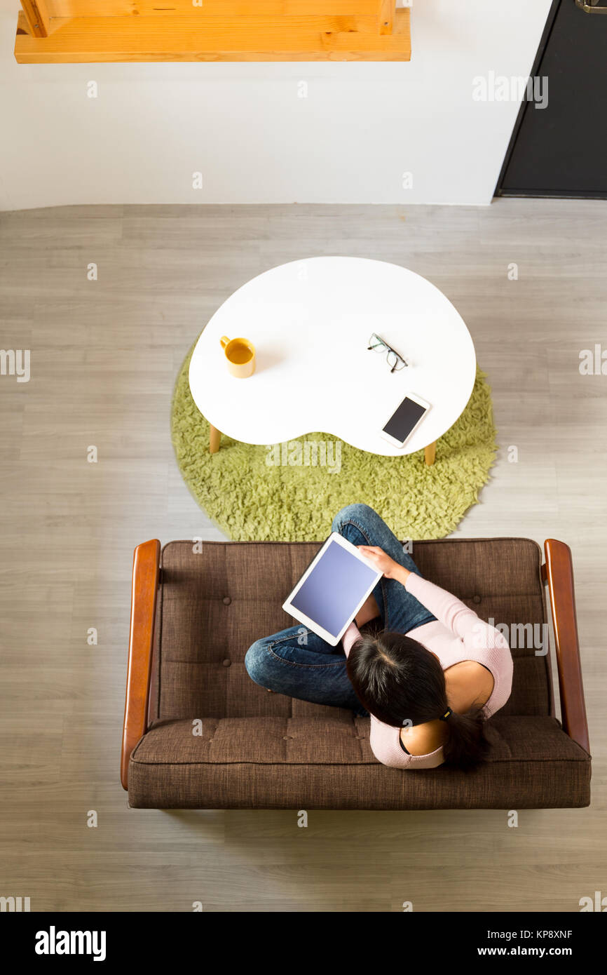 Vue de dessus de la femme l'utilisation de la tablet pc et sitting on sofa Banque D'Images