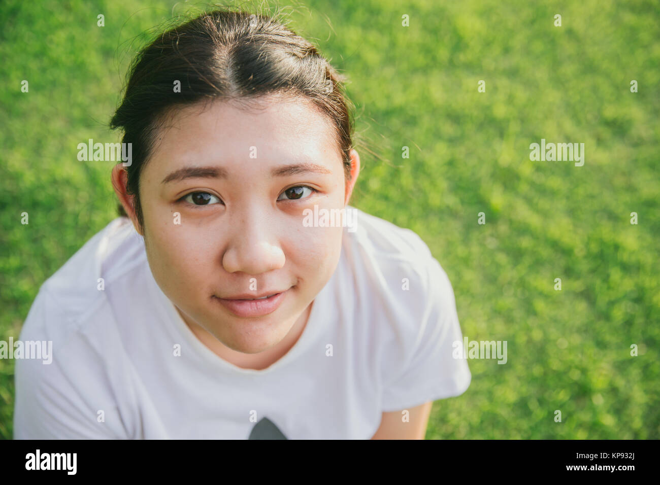 Jeune ado asiatique innocent sourire avec fond d'herbe verte libre de la tête et de la face Banque D'Images