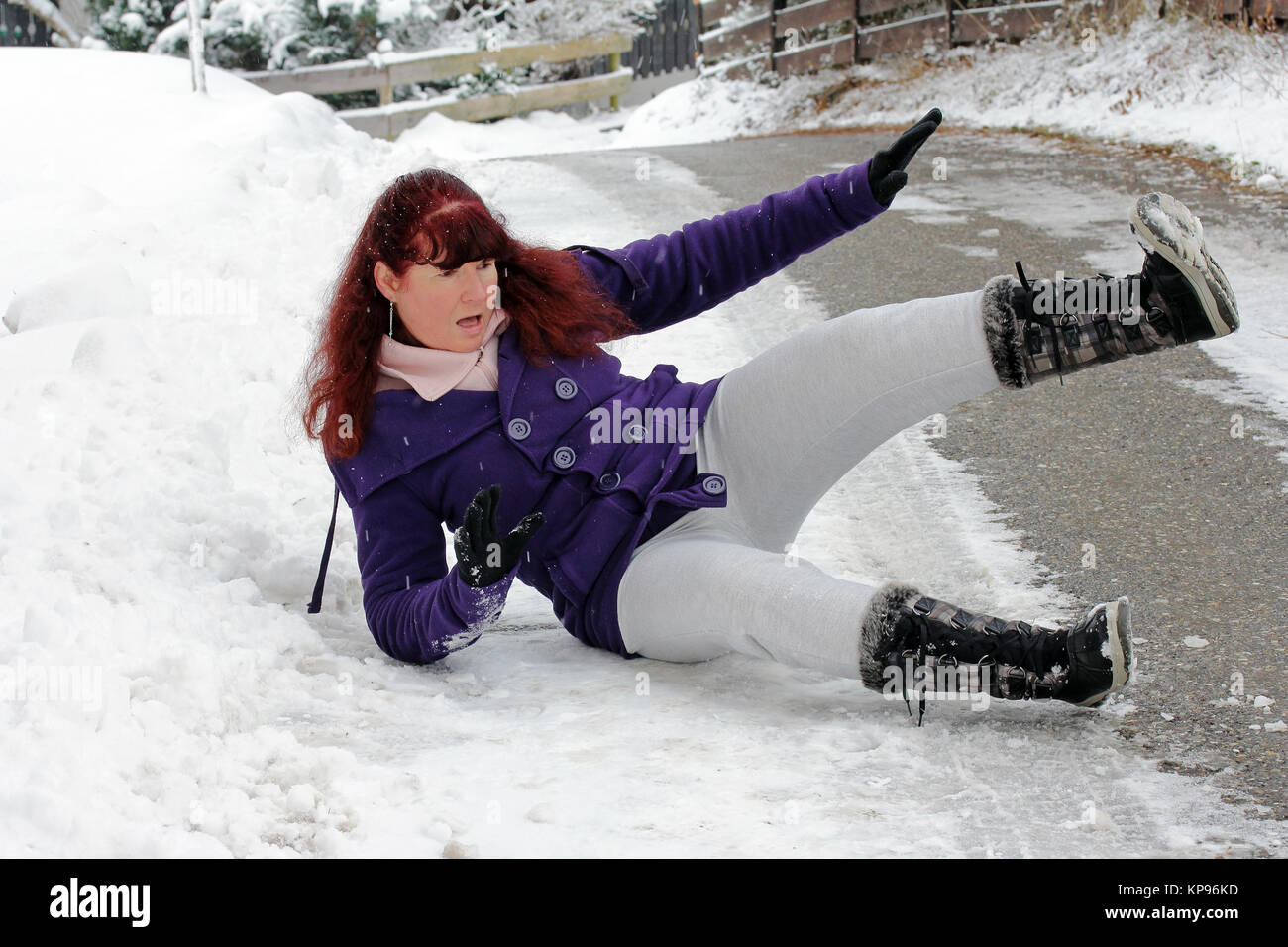 Risque d'accidents en hiver - une femme a glissé sur une route enneigée Banque D'Images