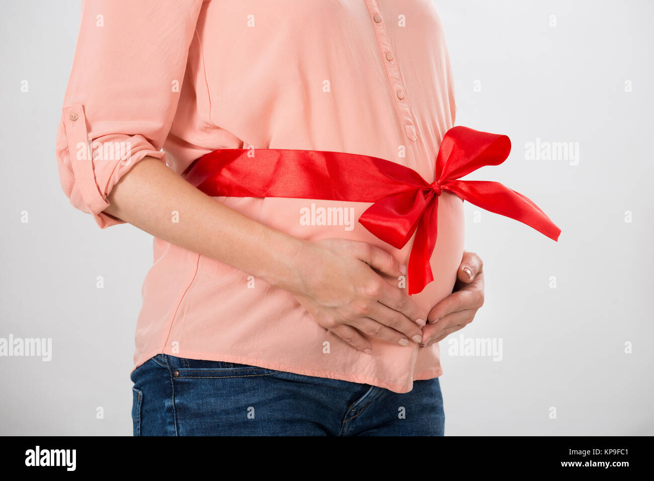 Femme enceinte avec ruban rouge liée au ventre Photo Stock - Alamy