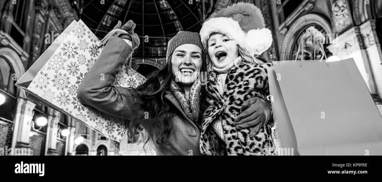 Sur une énorme vente de Noël dans la capitale italienne de la mode. Portrait of happy young mother and daughter voyageurs dans la Galleria Vittorio Emanuele II à Milan Banque D'Images