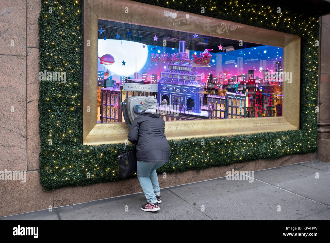 Une femme à la recherche à travers une loupe pour un close up de Macy's Herald Square à la fenêtre de Noël à Manhattan, New York City. Banque D'Images