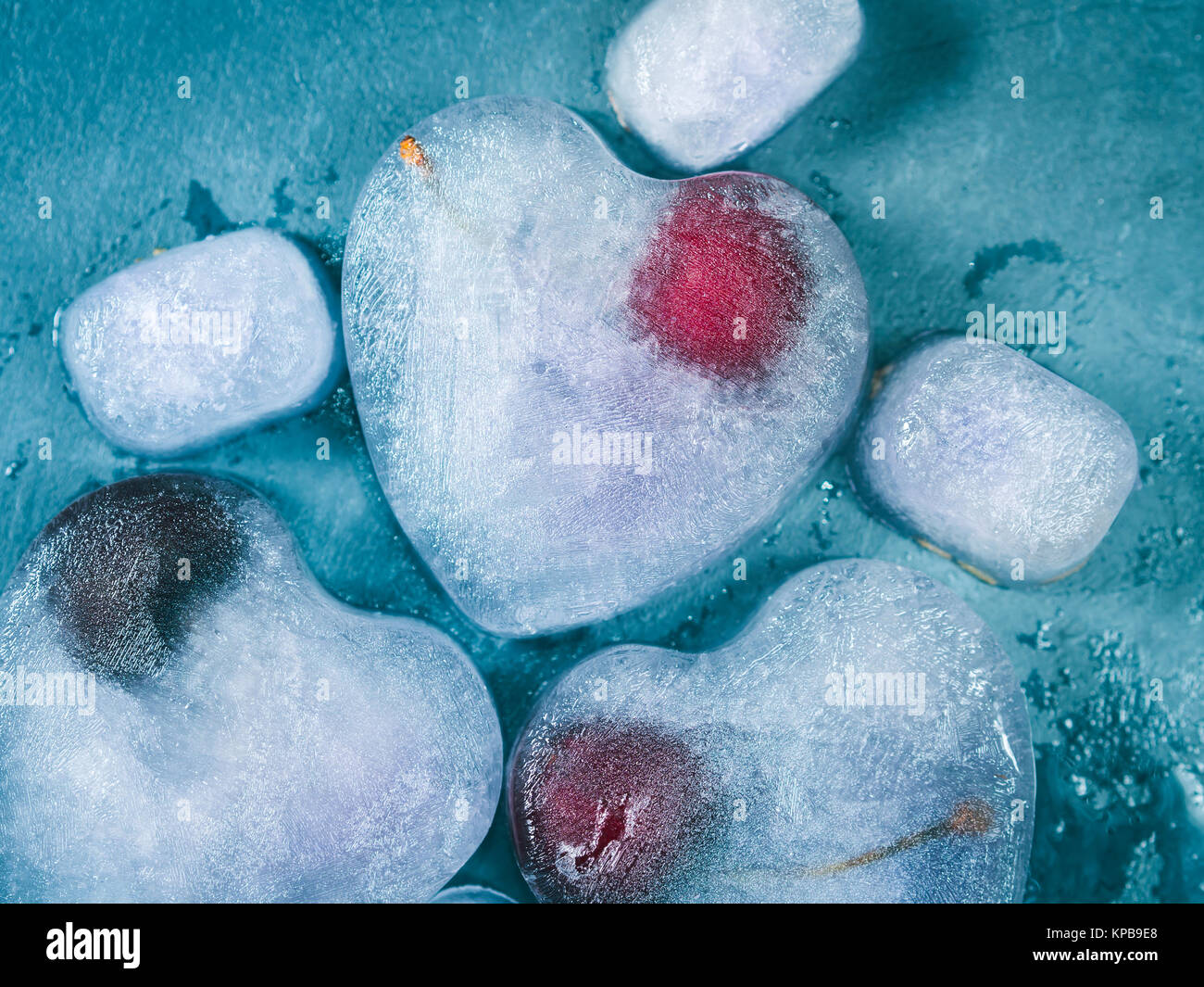 Sirop de lavande en forme de coeur avec des cubes de glace cerise congelée sur fond texturé bleu. Tonique Banque D'Images