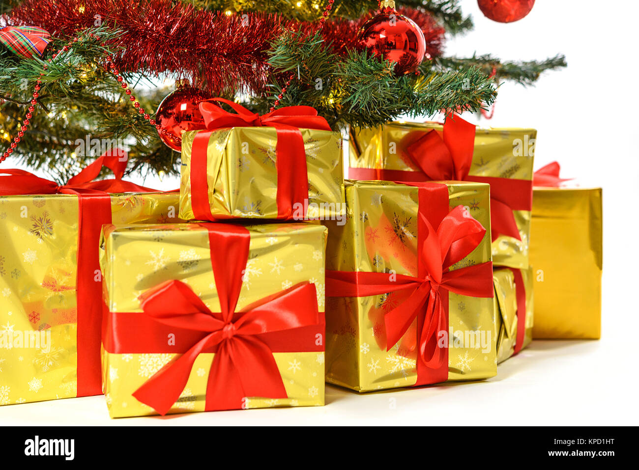 Cadeaux de luxe en boîte en or avec ruban rouge sous un arbre de Noël avec des boules rouges, des arcs et des lumières en close-up Banque D'Images