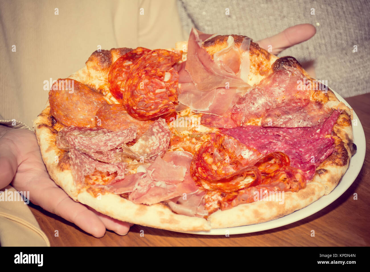 Les hommes&# 39 s mains tiennent italien pizza au jambon et salami Banque D'Images