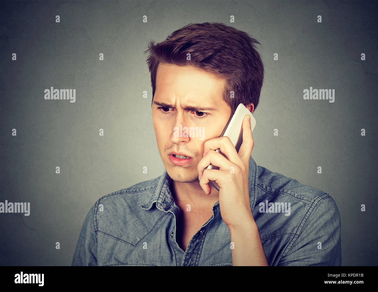 Jeune homme à la recherche de la frustration lors de l'obtention d'une mauvaise nouvelle sur un téléphone. Banque D'Images