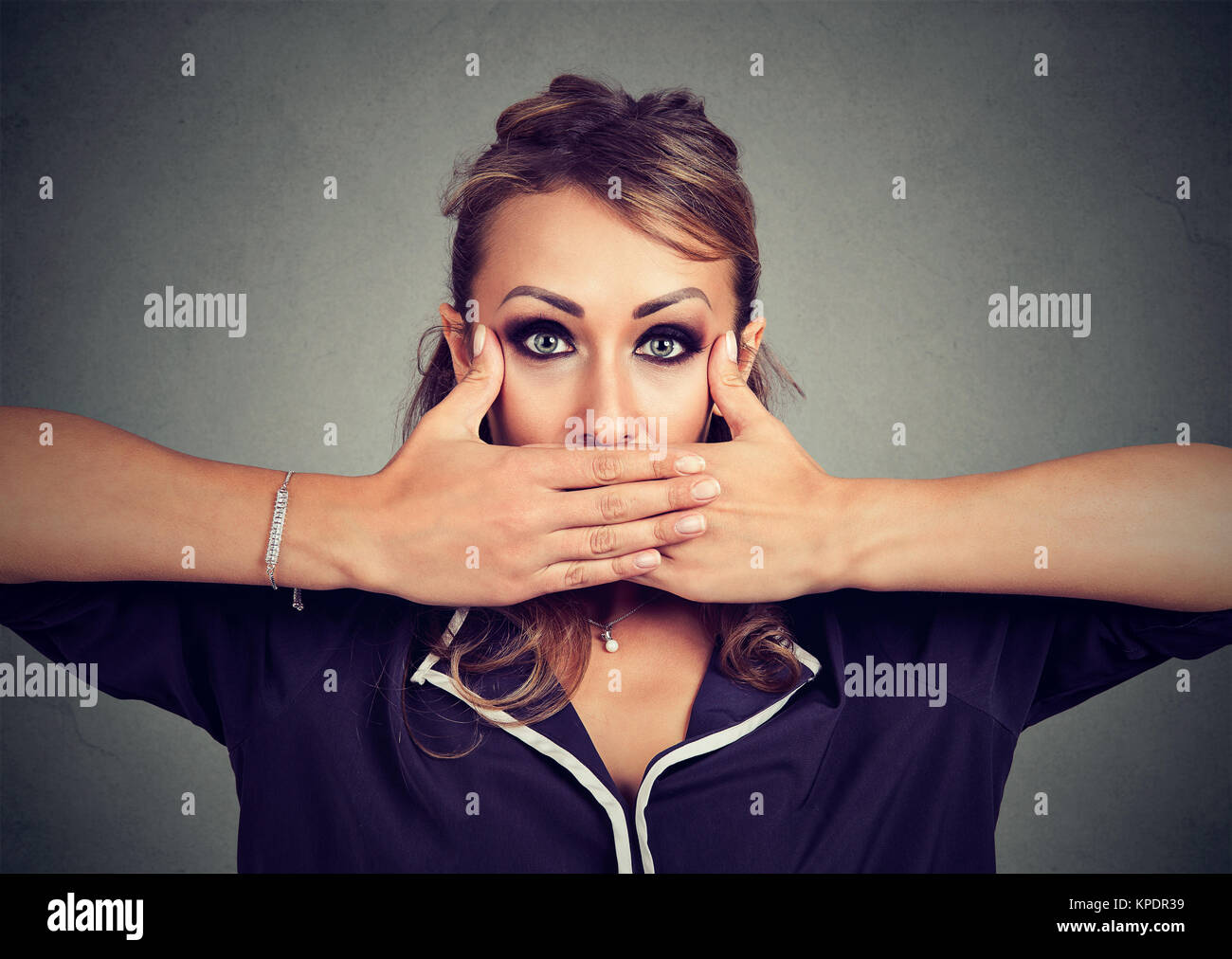 Jeune femme couvrant la bouche avec les mains en mesure d'exprimer des sentiments réels et à la recherche à l'appareil photo. Banque D'Images