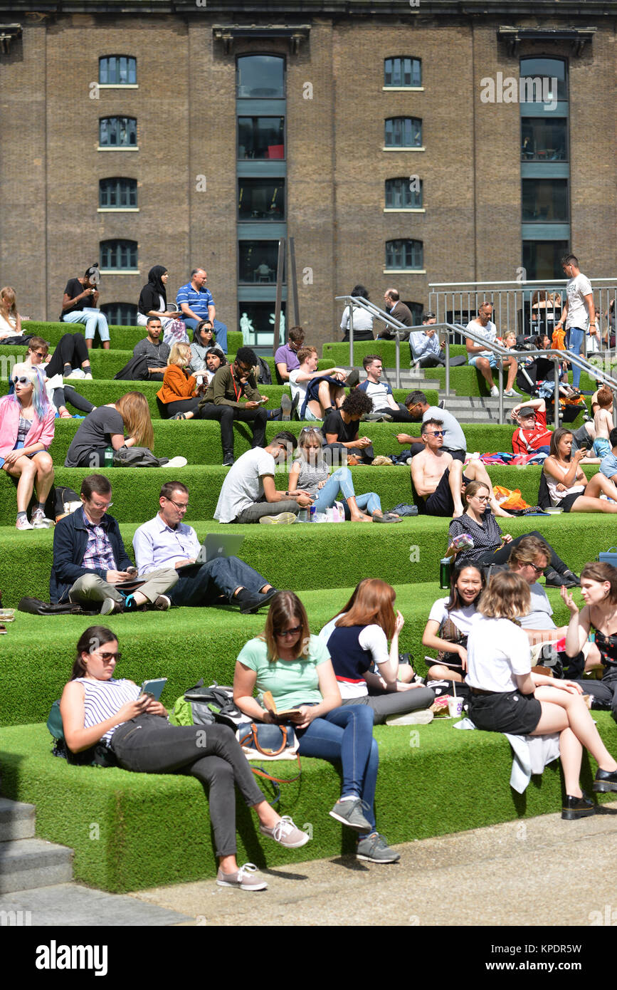 Les gens se détendre et profiter du soleil près de Central St Martins, Kings Cross Londres. Banque D'Images