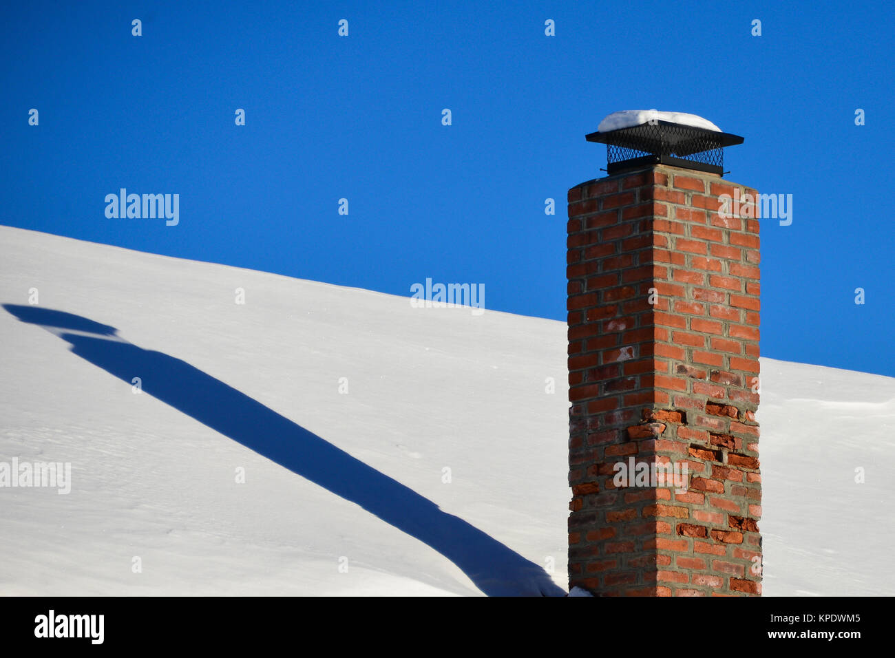 Cheminée en brique rouge en décomposition sur un toit couvert de neige dans la région de spéculateur, NY USA Banque D'Images