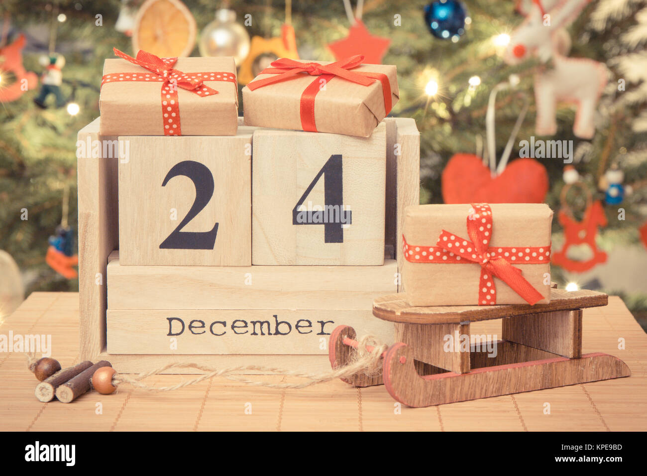 Vintage photo, ce jour 24 Décembre sur cube calendrier, les cadeaux emballés avec des rubans et l'arbre de Noël avec des lumières et de la décoration, la veille de Noël concept de