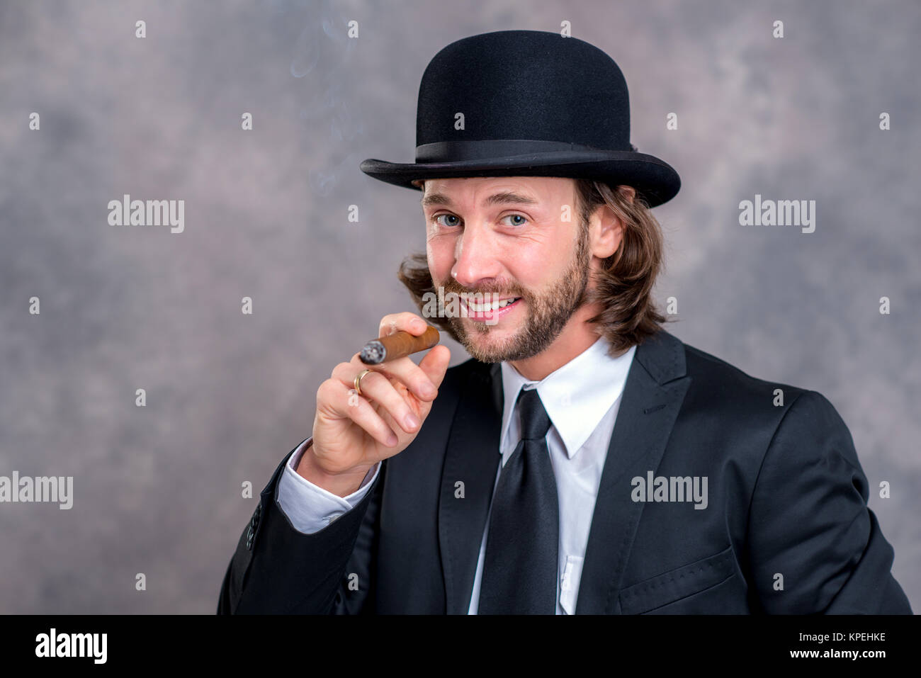 Jeune homme avec chapeau melon en costume noir fumeurs de cigare gros Photo  Stock - Alamy