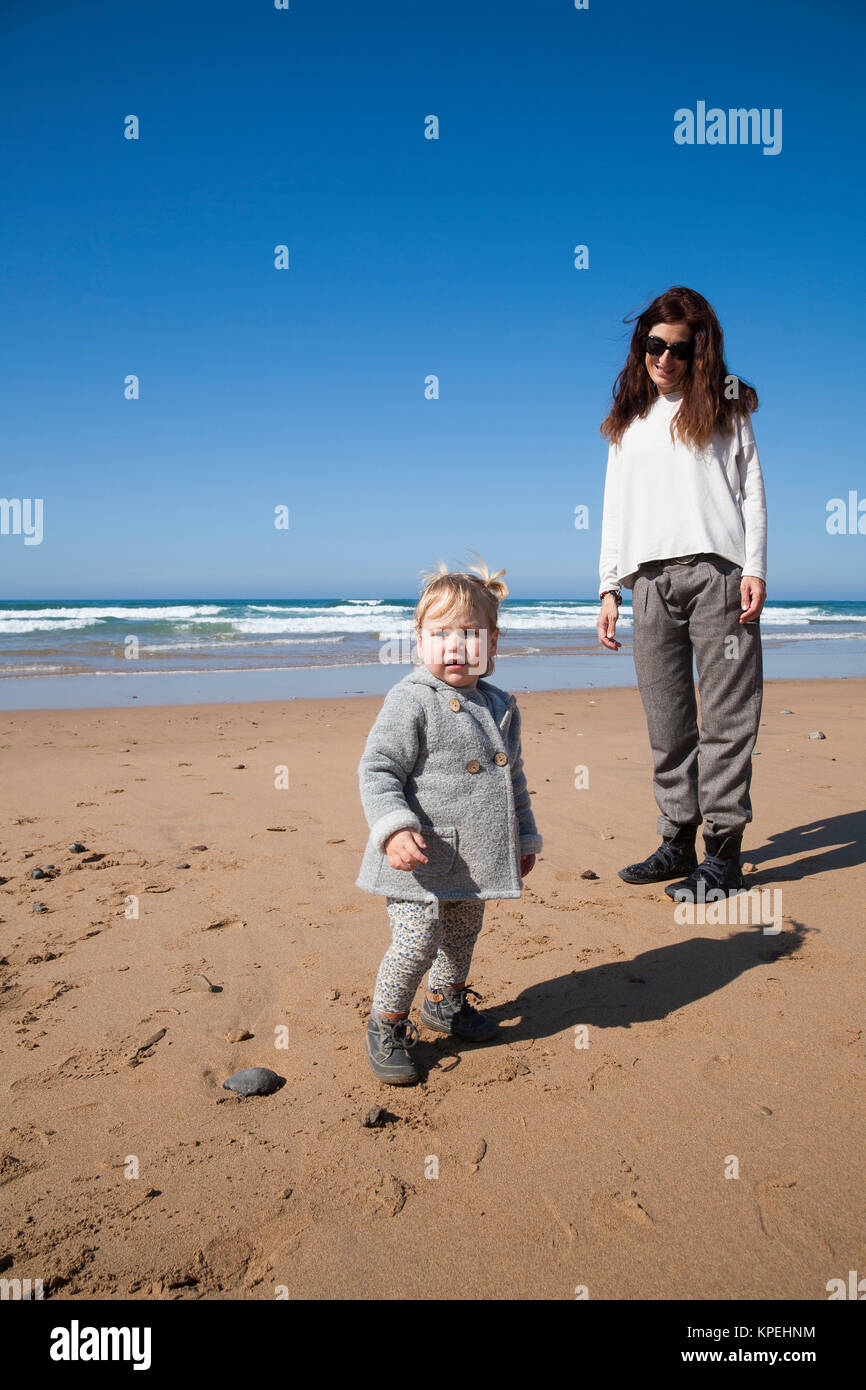 Le bébé et la mère en beach looking at camera Banque D'Images