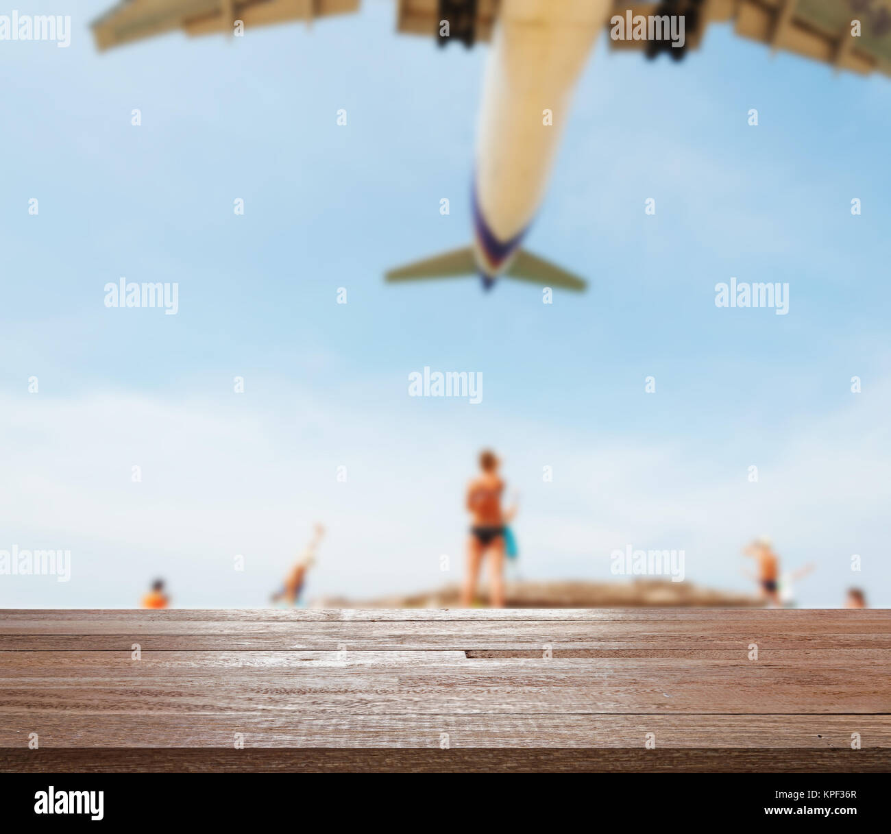 Table en bois sur la mer bleue floue et plage de sable blanc avec certaines personnes ou d'avion. Banque D'Images