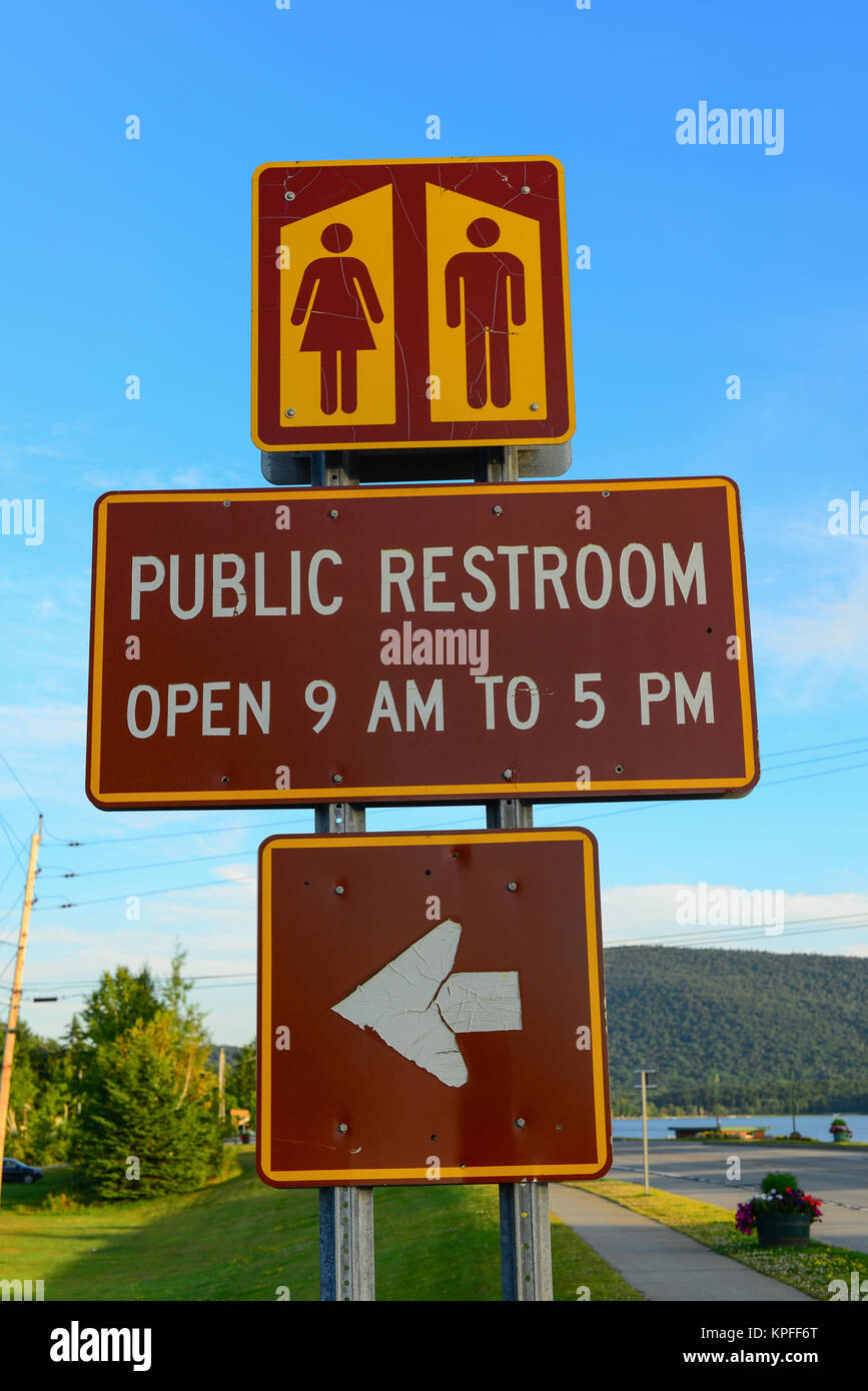 Toilette publique heures signe et sens de spéculateur, NY USA à la plage sur le lac Pleasant dans le parc des Adirondack. Banque D'Images