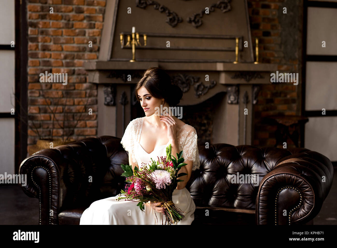 Belle robe de mariée assis sur une chaise à l'intérieur dans dark studio intérieur comme à la maison. Banque D'Images