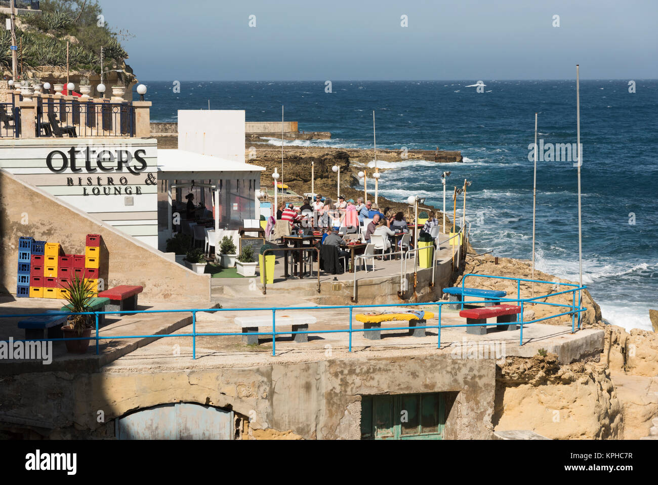 Les gens de manger à des tables au bord de l'eau au restaurant Lounge Bistro les loutres de la baie de Marsalforn Gozo Malte Banque D'Images