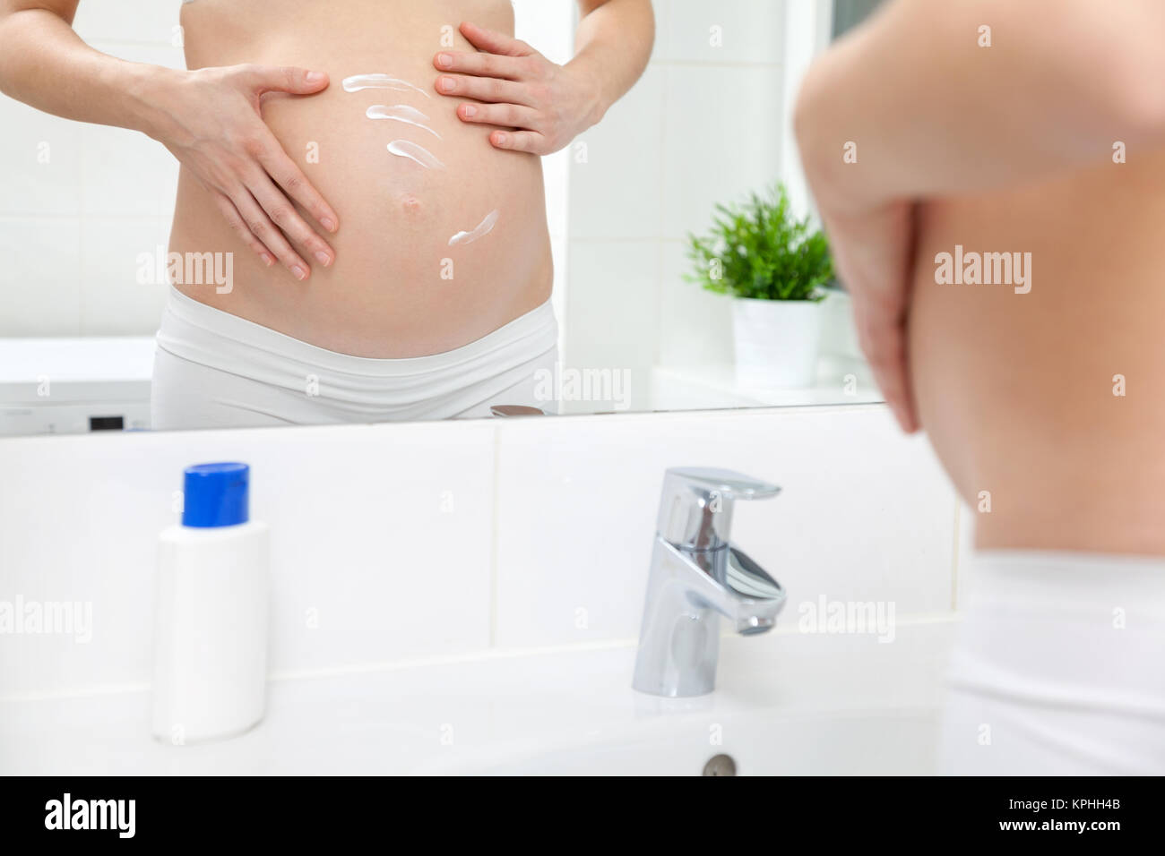 Femme enceinte en miroir de salle de bains Banque D'Images