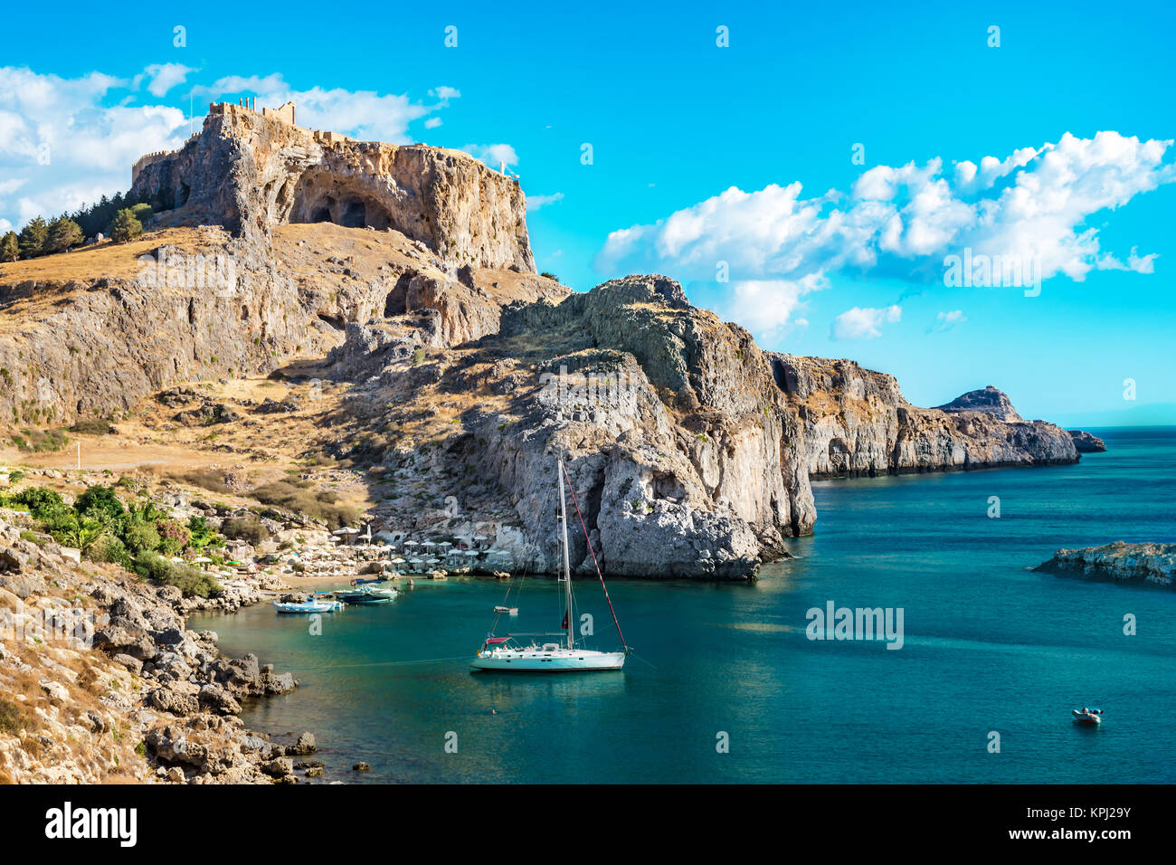 Belle la baie de Saint Paul avec des bateaux, de l'Acropole de Lindos en arrière-plan (Rhodes, Grèce) Banque D'Images