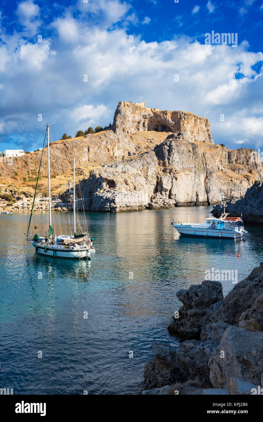 Voiliers dans la baie de Saint Paul, ciel nuageux ciel bleu, Lindos acropole en arrière-plan (Rhodes, Grèce) Banque D'Images