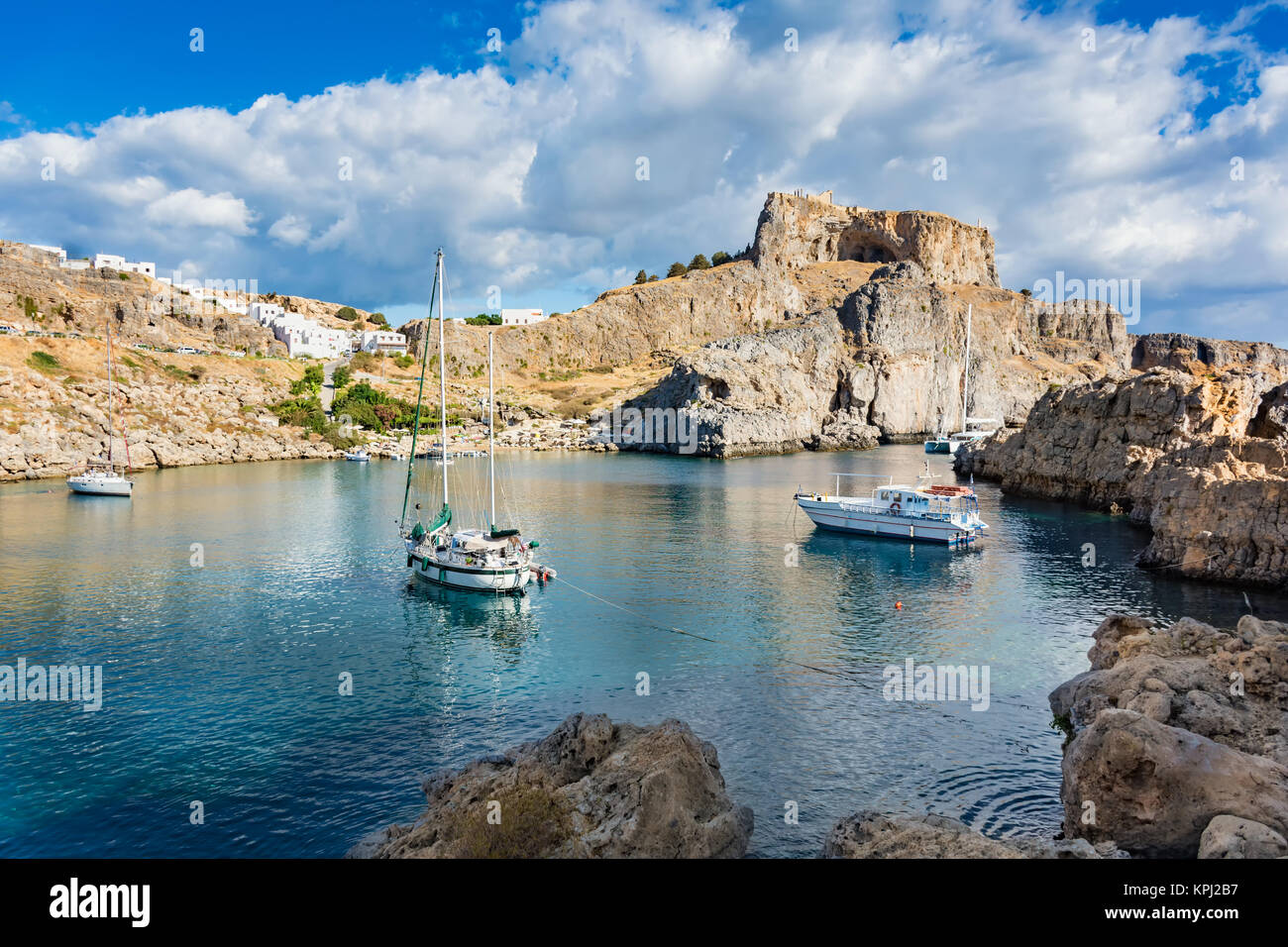Voiliers dans la baie de Saint Paul, ciel nuageux ciel bleu, Lindos acropole en arrière-plan (Rhodes, Grèce) Banque D'Images