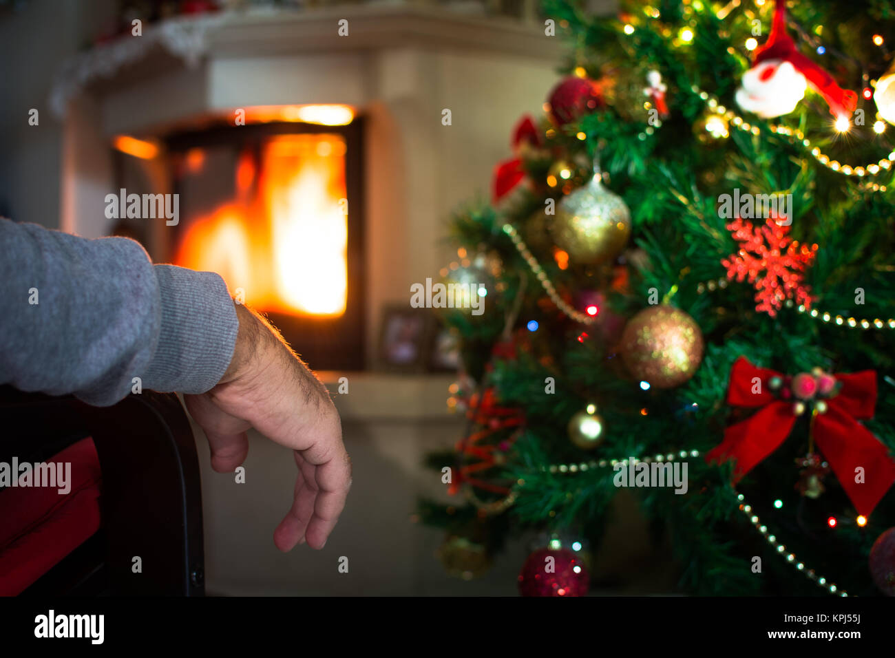 Homme seul la main devant la cheminée avec arbre de Noël. Banque D'Images