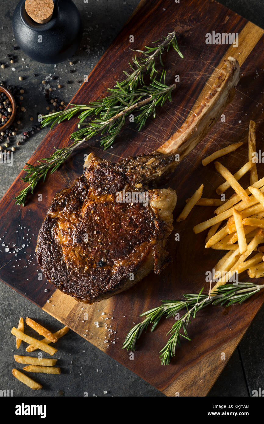 Les steaks cuits Tomahawk nourri à l'herbe avec des frites et de romarin Banque D'Images