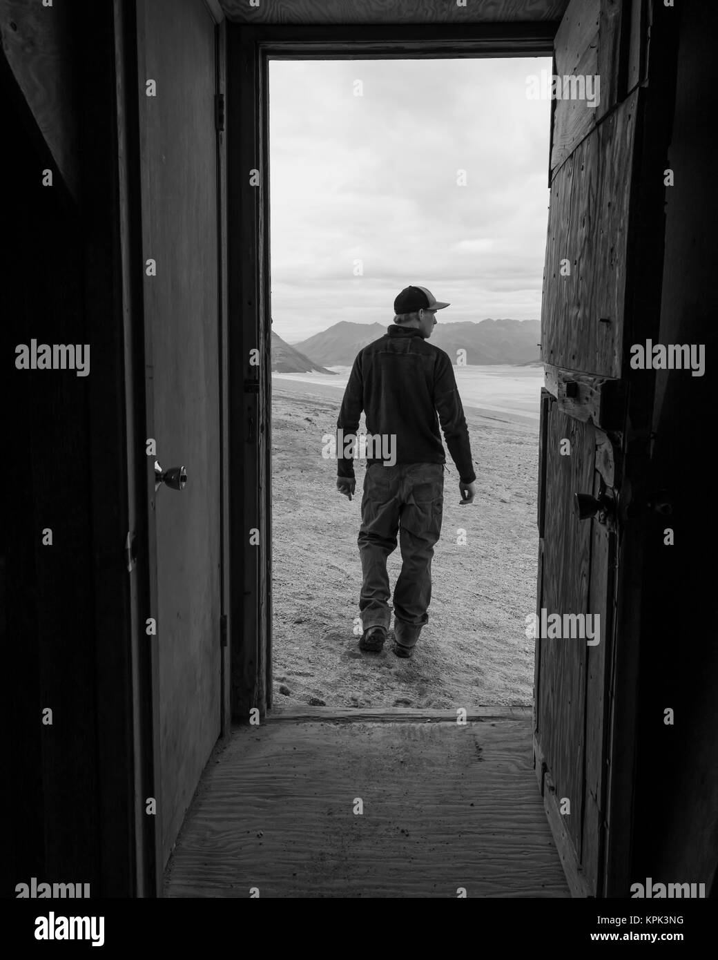 Un homme et la vallée de dix mille fume est encadrée par la porte d'un des refuges de montagne en boulangerie Katmai National Park Banque D'Images