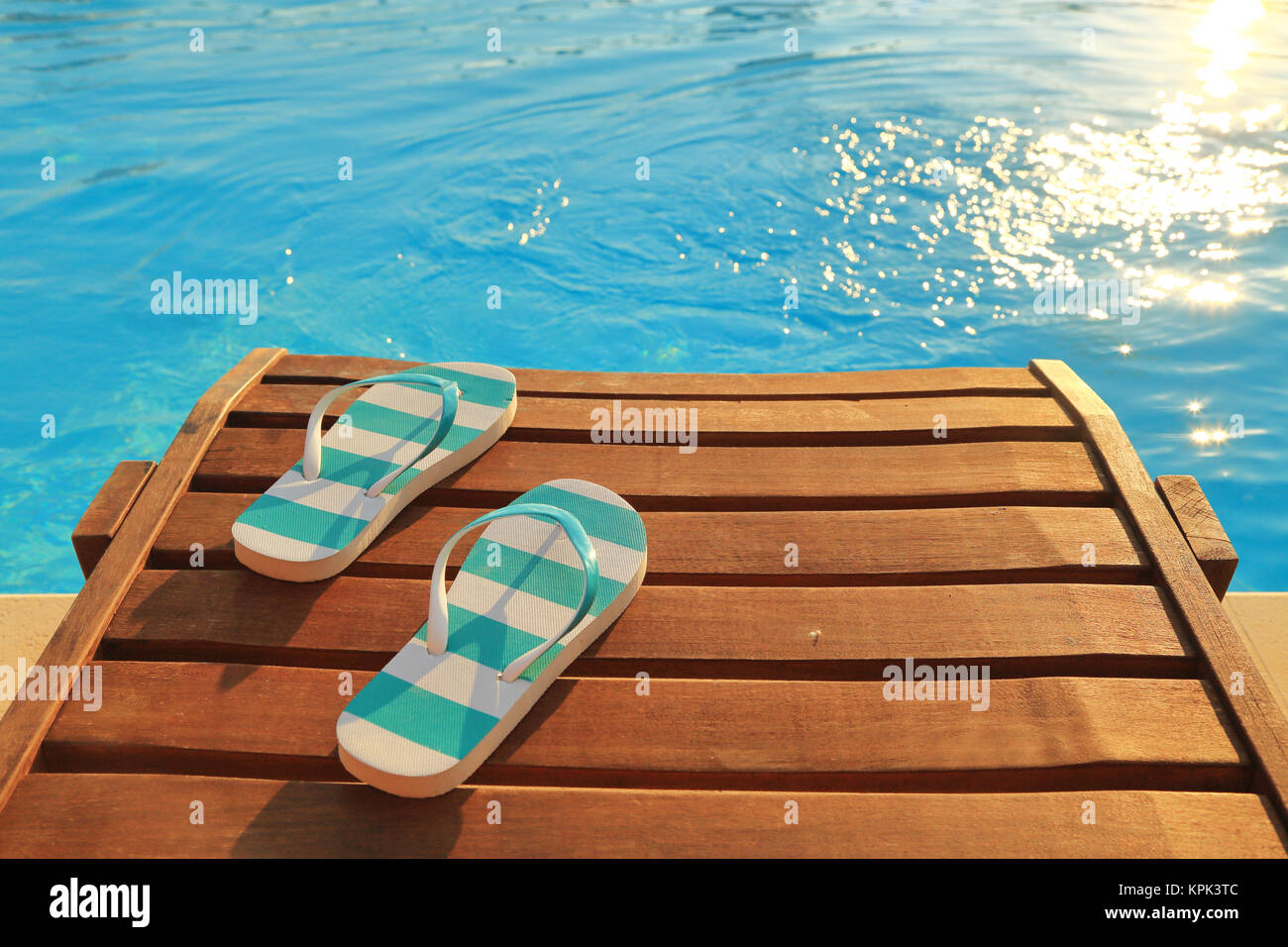 Tongs en bois sur l'eau et de bronzage Photo Stock - Alamy