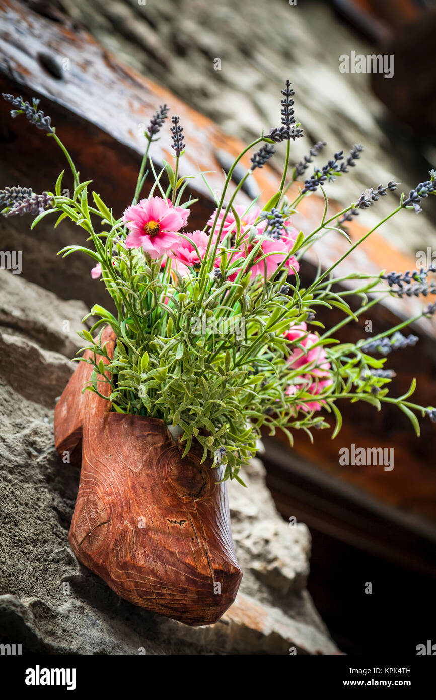 Un pot de fleurs sculptées de sabots de bois le long d'anciennes rues pavées de Dolonne, près de Courmayeur, vallée d'aoste, Italie Banque D'Images