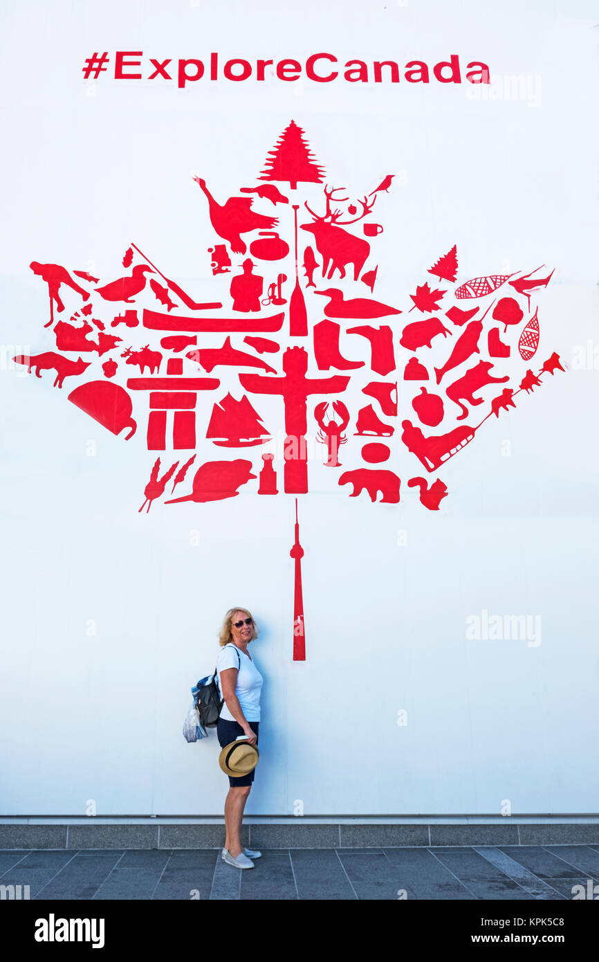 Une femme s'en vertu d'une feuille d'érable rouge et blanc mural de la promotion du tourisme canadien ; Vancouver, Colombie-Britannique, Canada Banque D'Images