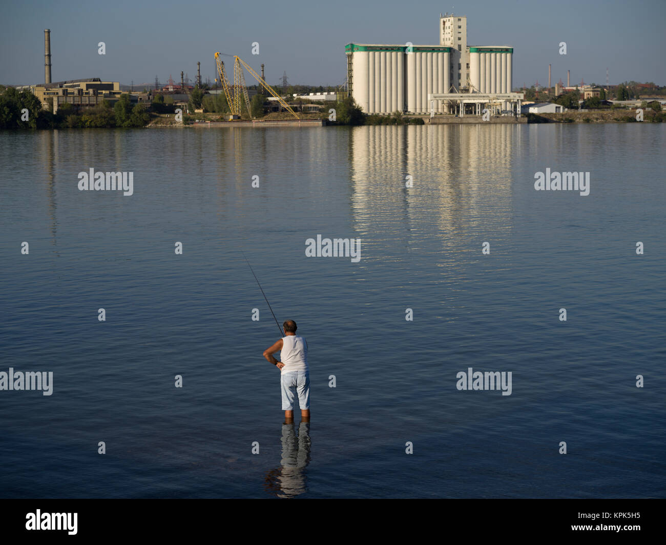 Un homme se tient dans l'eau jusqu'aux genoux dans le Danube la pêche dans son short et t-shirt ; Kladovo, District de Bor, en Serbie Banque D'Images