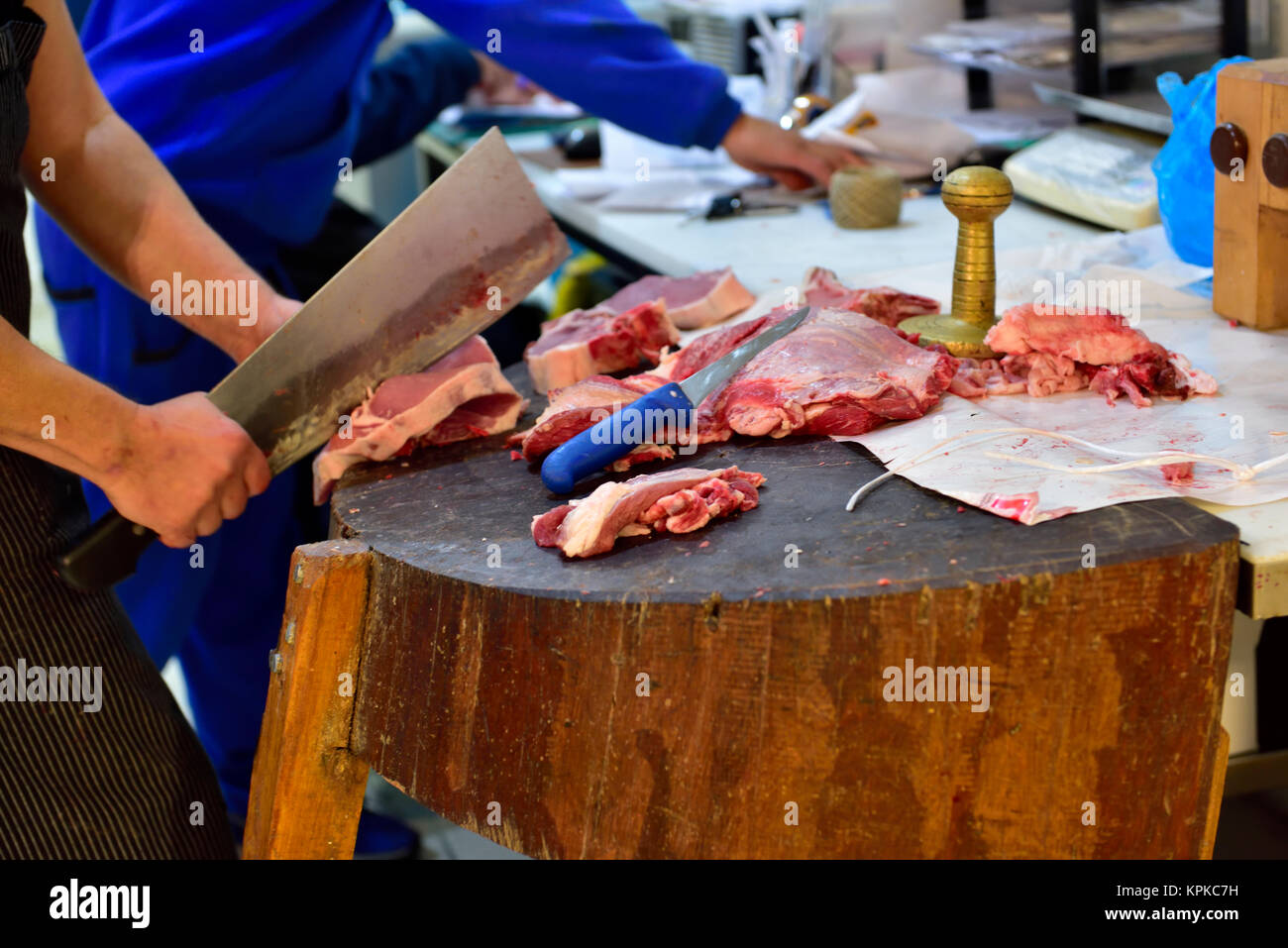 Butcher en utilisant cleaver pour découper la viande sur bloc de bouchers à Athènes, Grèce centrale du marché de la viande Banque D'Images