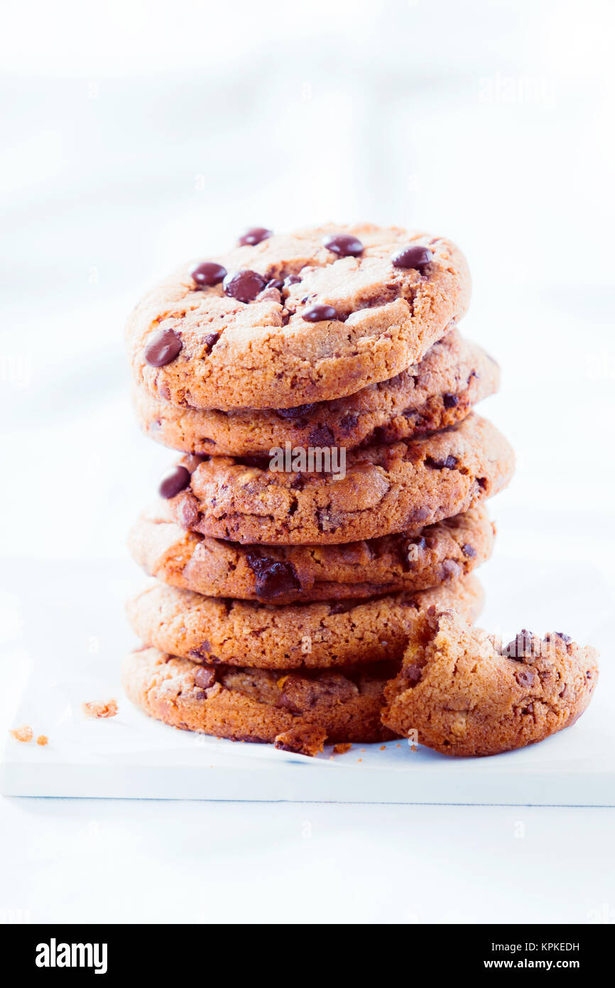 Pile de cookies au chocolat croquant avec les vestiges d'un mangé ou que l'un à côté sur un fond blanc texturé with copy space Banque D'Images