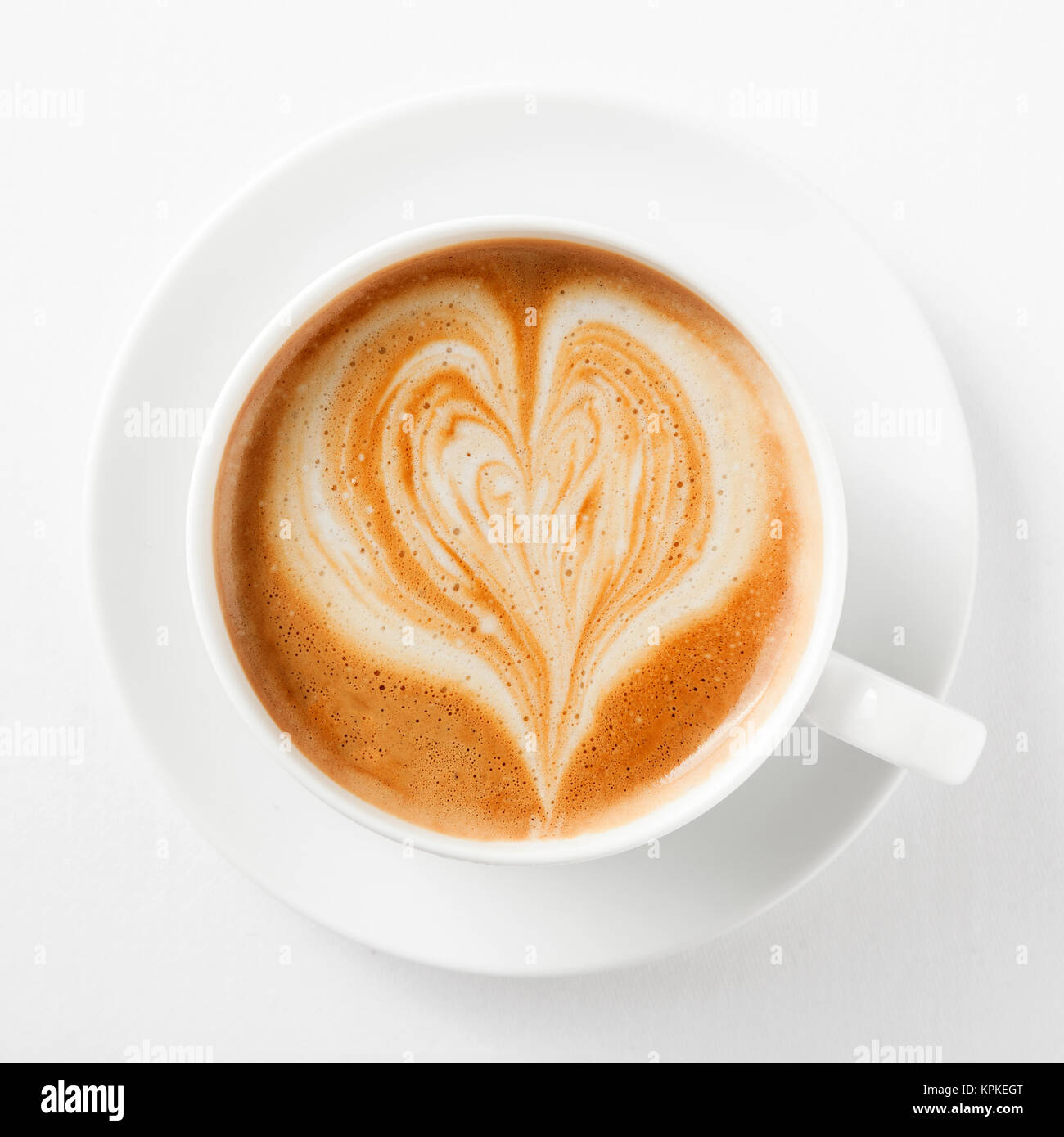 Tasse de cappuccino avec un cœur dans la voie lactée mousse qui s'est vue d'en haut dans une tasse et soucoupe blanc générique on white Banque D'Images
