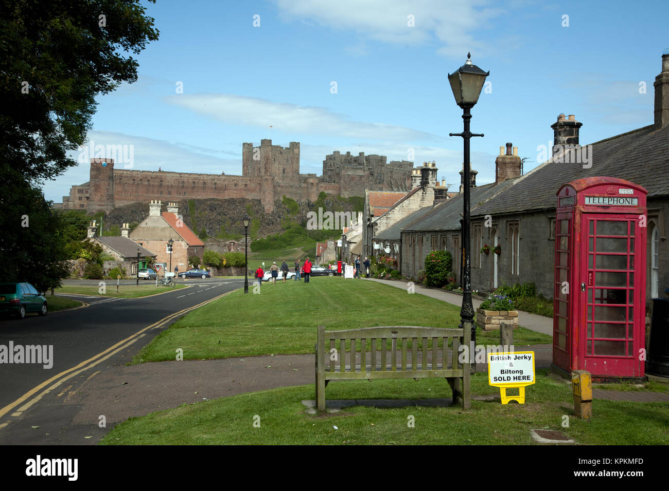 Village et château de Bamburgh, Northumberland, Angleterre. Vue vers le bas la rue Front rouge traditionnel avec K6 téléphone fort. Banque D'Images