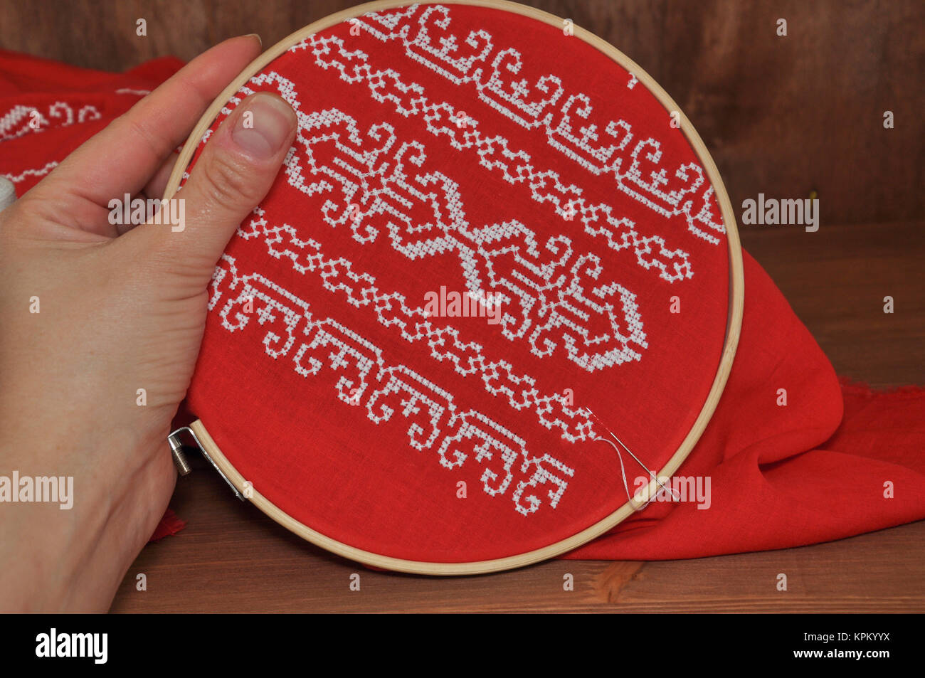 Croix broderie main sur tissu rouge avec un fil blanc Banque D'Images