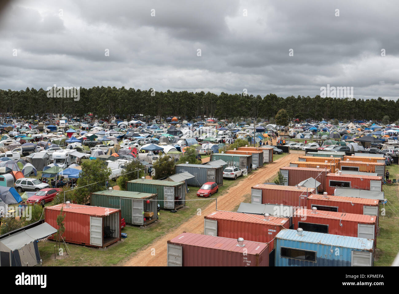 Vue aérienne de très grand festival de musique de camping contenant d'expédition hébergement tentes, caravanes, voitures et forêt en distance. Banque D'Images