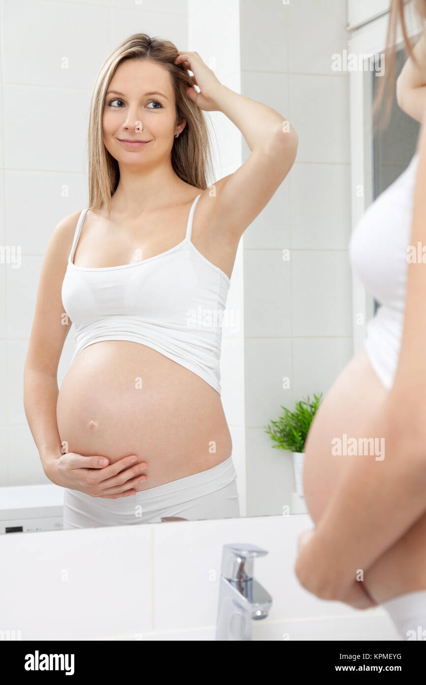 Femme enceinte en miroir de salle de bains Banque D'Images