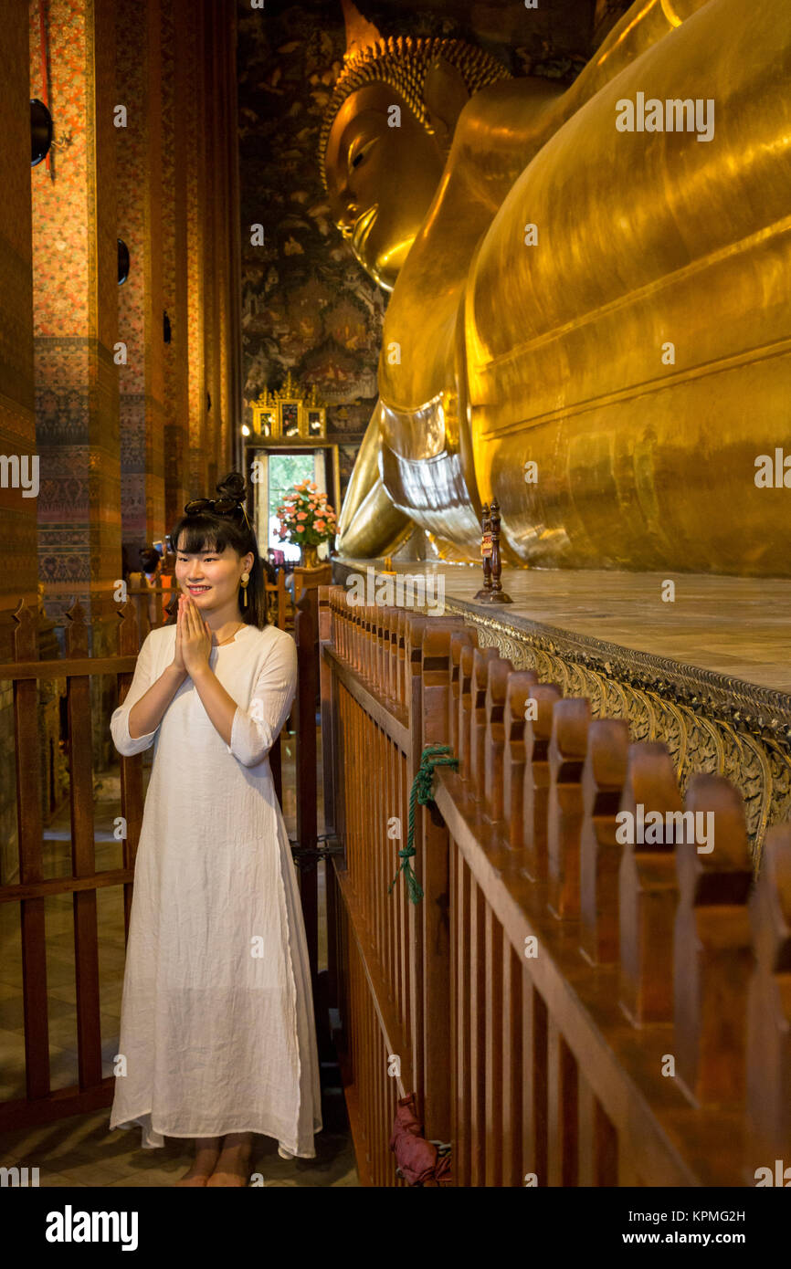 Bangkok, Thaïlande. Bouddha couché, Wat Pho temple complexe. Jeune femme ayant sa photo prise. Banque D'Images