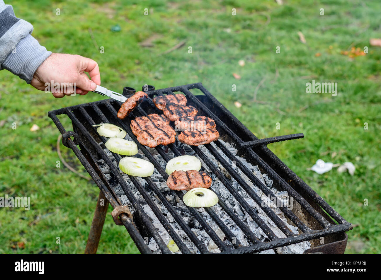 Barbecue extérieur. Les hommes&# 39 boulettes de viande au four dans la main sur le grill. Banque D'Images