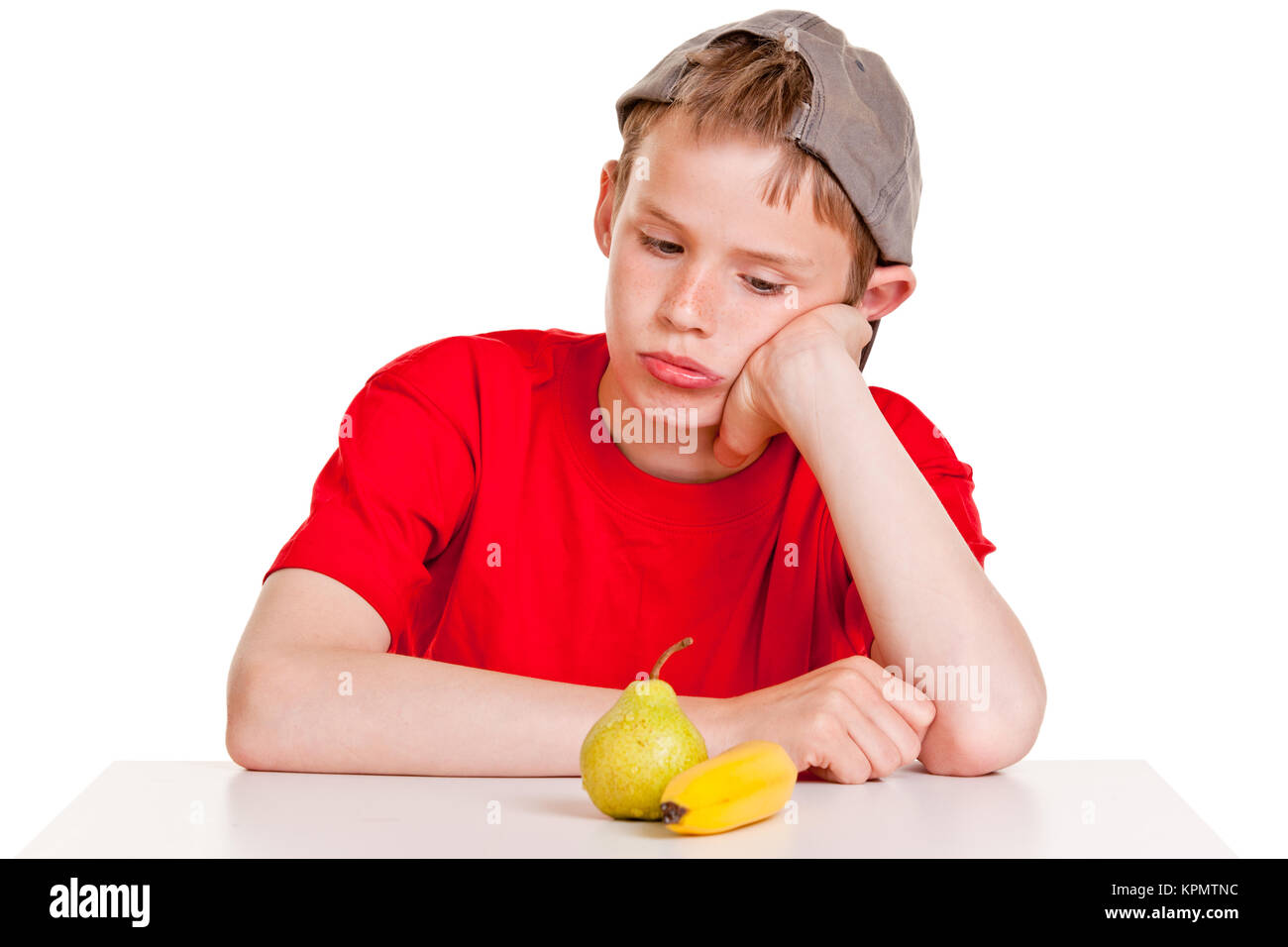 Jeune garçon morose regardant fixement une banane mûre et de poire Banque D'Images