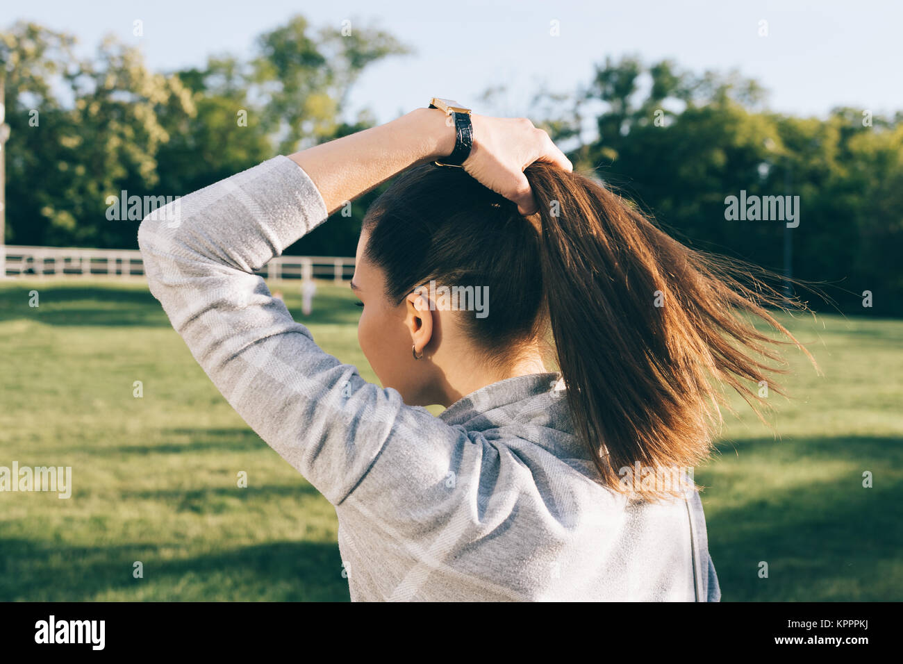 Jeune femme avec les cheveux bruns dans un parc ensoleillé, vue de l'arrière Banque D'Images