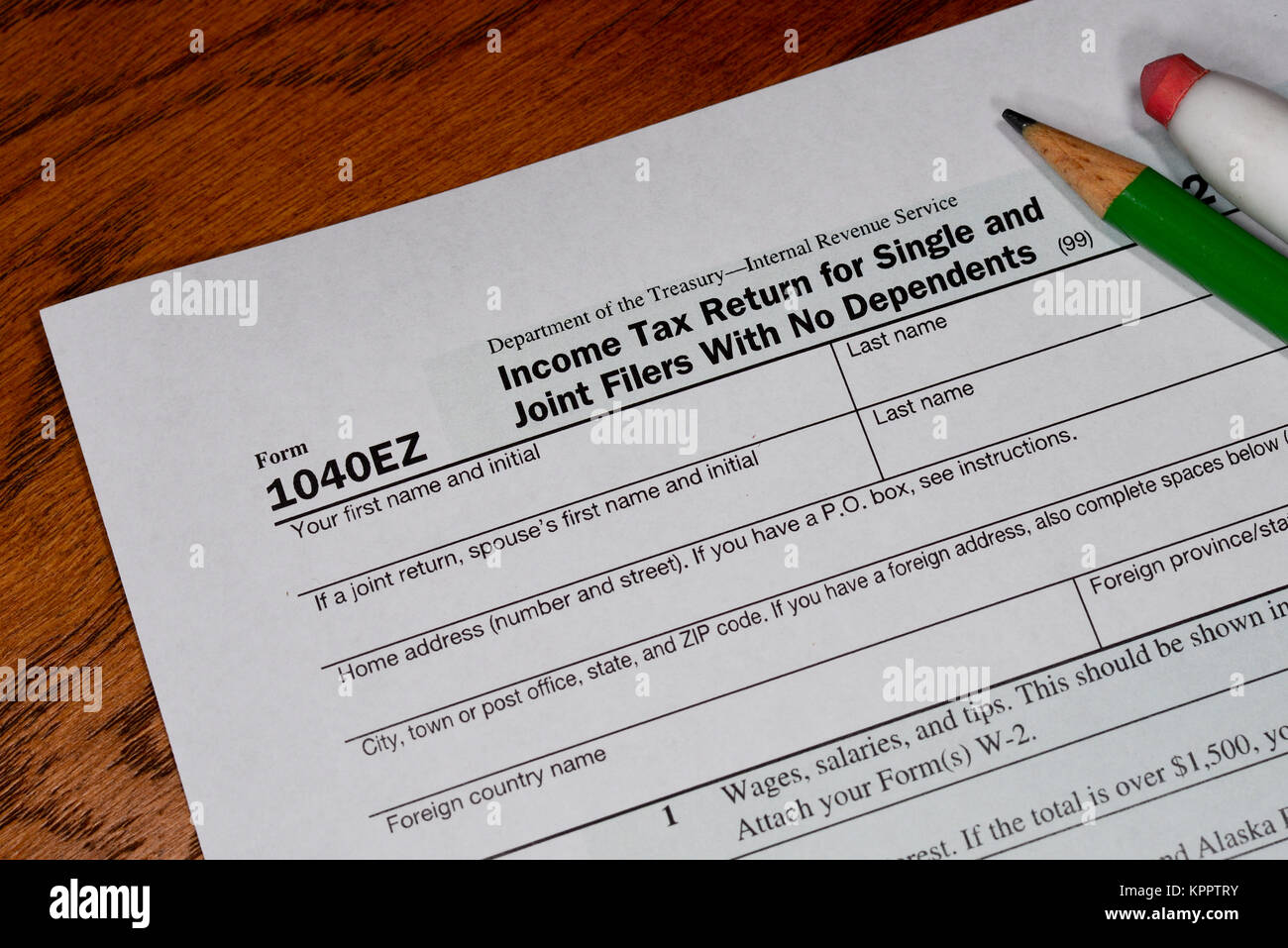 Version simple de l'impôt sur le revenu pour les particuliers - formulaire 1040EZ - avec un crayon et une gomme sur un bureau en bois. Banque D'Images