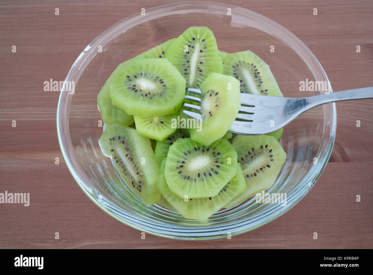 Bol avec plein riche en vitamines les kiwis en tranches et tablier isolé sur fond de bois Banque D'Images