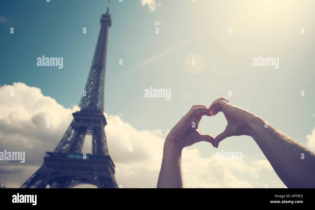 Love in Paris - mains formant un cœur en face de la Tour Eiffel Banque D'Images