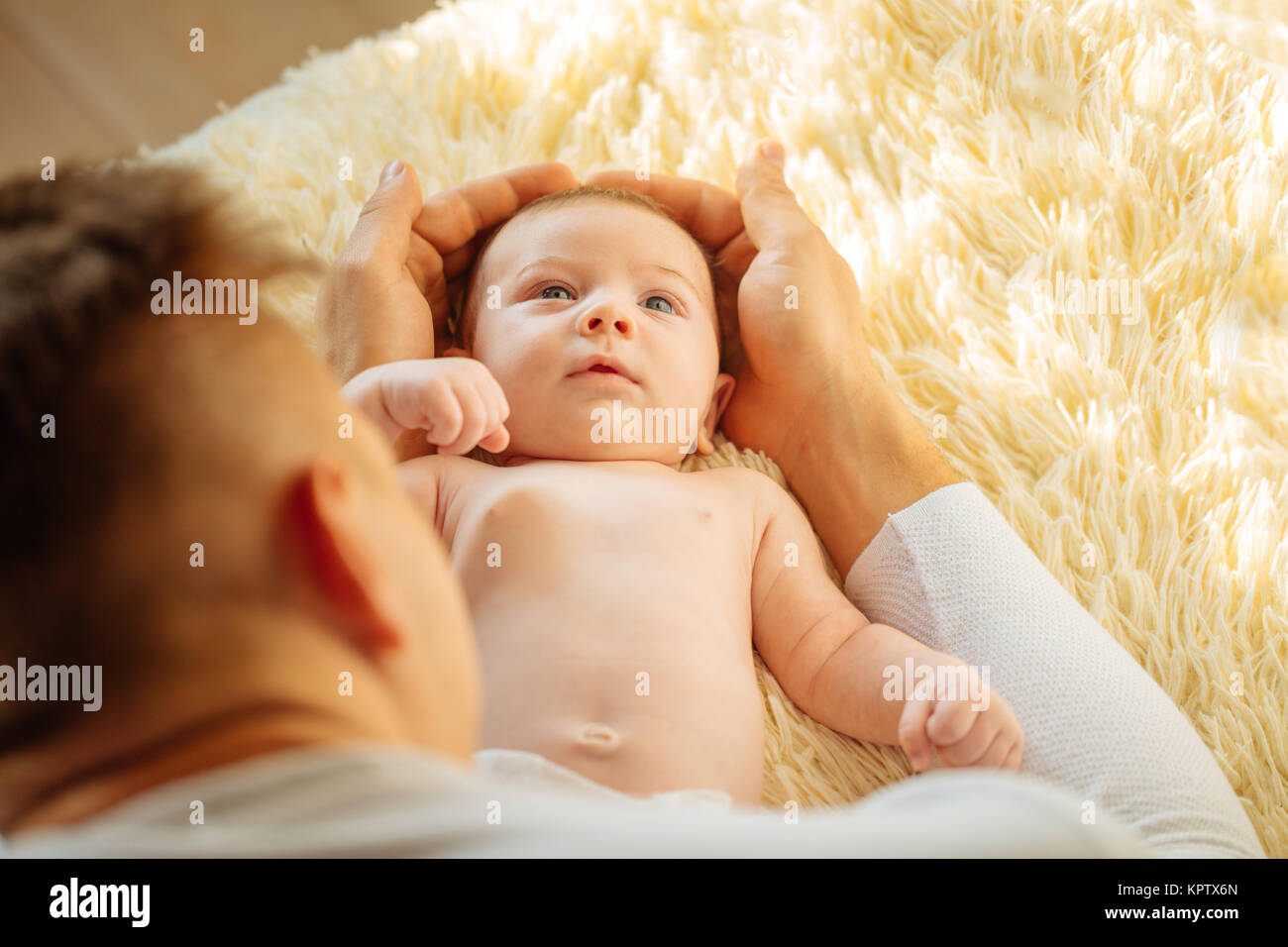 Baby looking at camera, jeter sur couverture blanche Banque D'Images