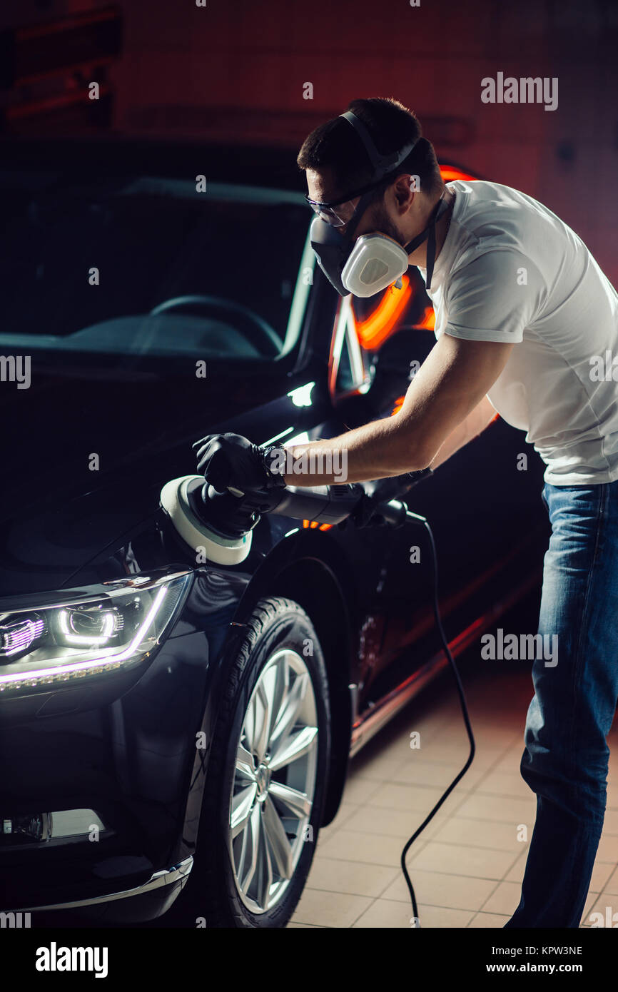 Esthétique auto - homme avec polisseuse orbitale en atelier de réparation automobile. Focus sélectif. Banque D'Images