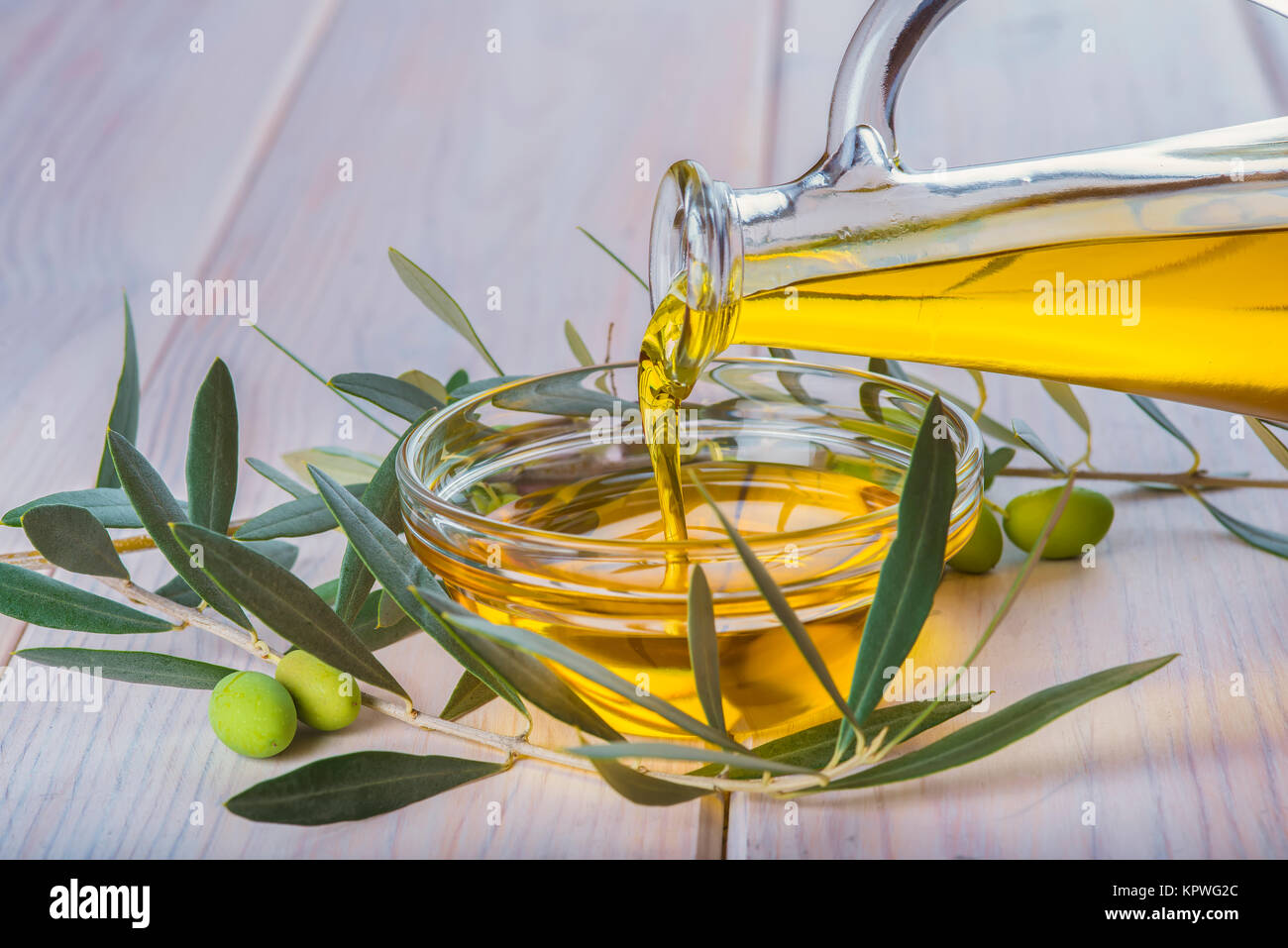 Verser la bouteille de l'huile d'olive vierge extra dans un bol Banque D'Images