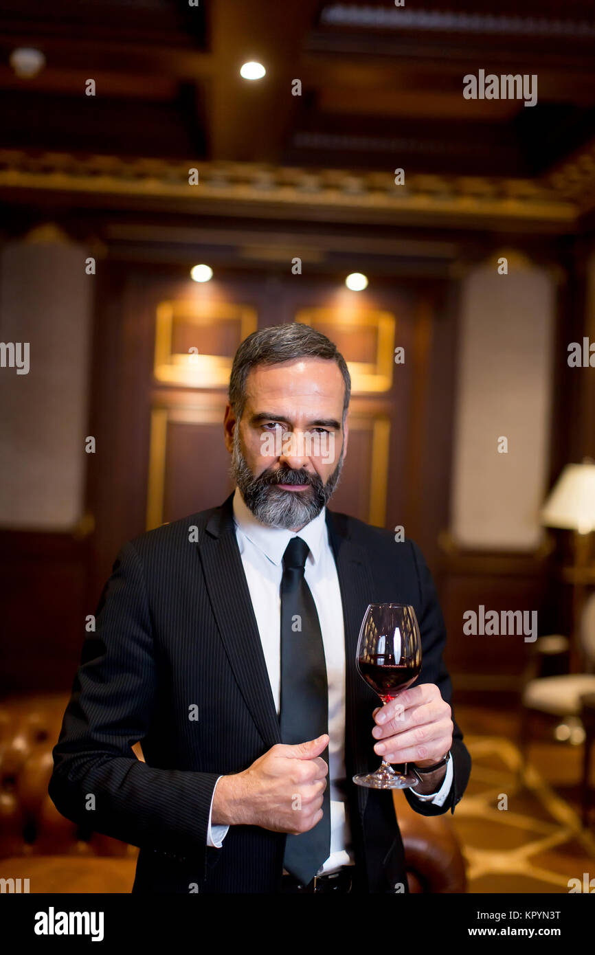 Beau elegant businessman drinking red wine in bar Banque D'Images